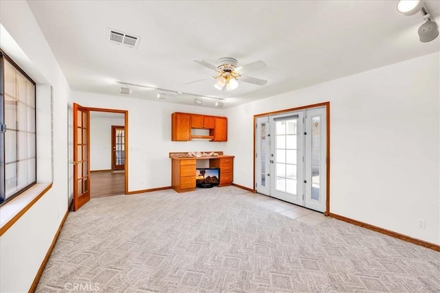 unfurnished living room with light colored carpet, baseboards, visible vents, and french doors