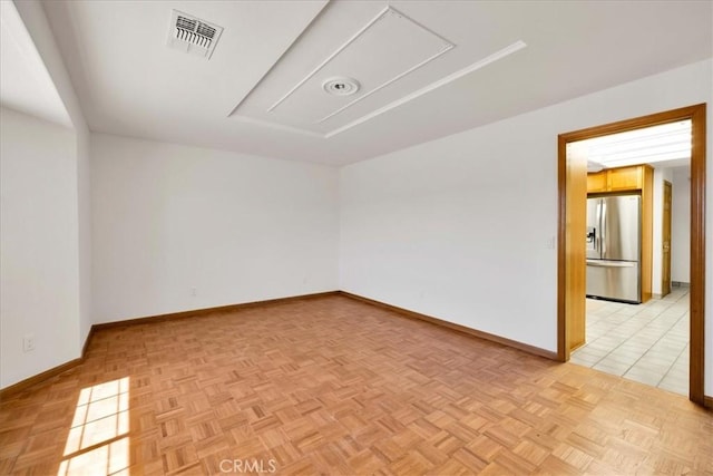 empty room featuring visible vents, attic access, and baseboards