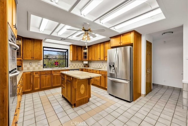 kitchen with light countertops, appliances with stainless steel finishes, backsplash, and brown cabinets