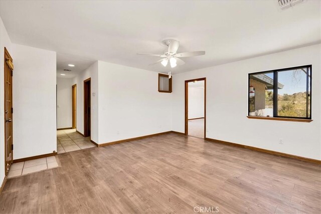 empty room with light wood-style floors, baseboards, a ceiling fan, and visible vents