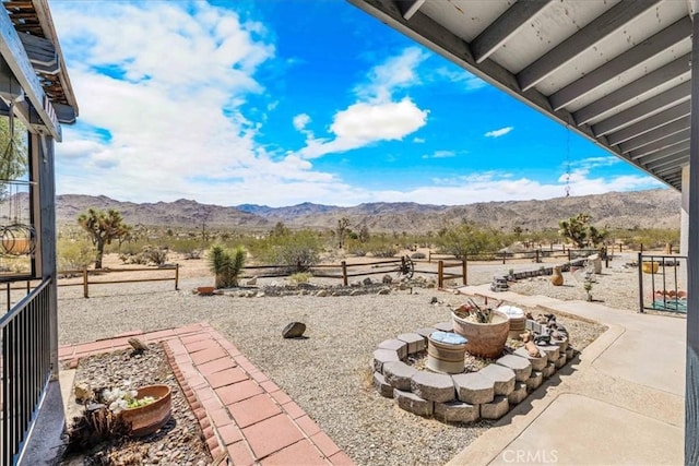 view of patio / terrace with a rural view, fence, and a mountain view