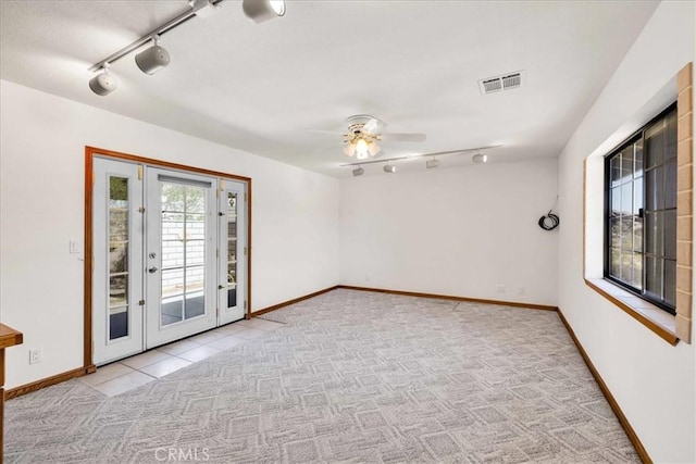 empty room with visible vents, rail lighting, ceiling fan, and light colored carpet