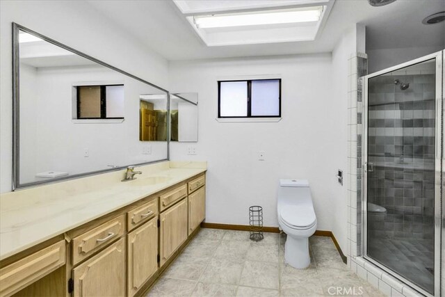 full bath with vanity, baseboards, a stall shower, and toilet