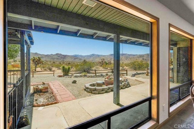 doorway with beamed ceiling, a mountain view, and wood finished floors