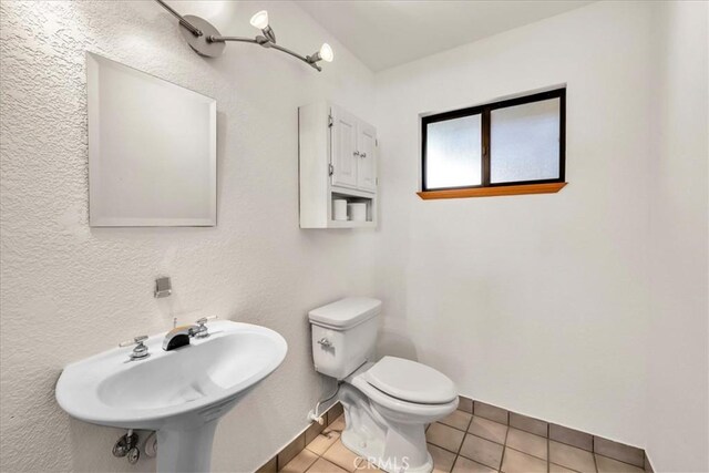 bathroom featuring a sink, tile patterned floors, baseboards, and toilet