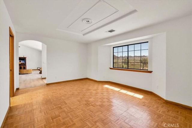 unfurnished room with arched walkways, baseboards, attic access, and visible vents