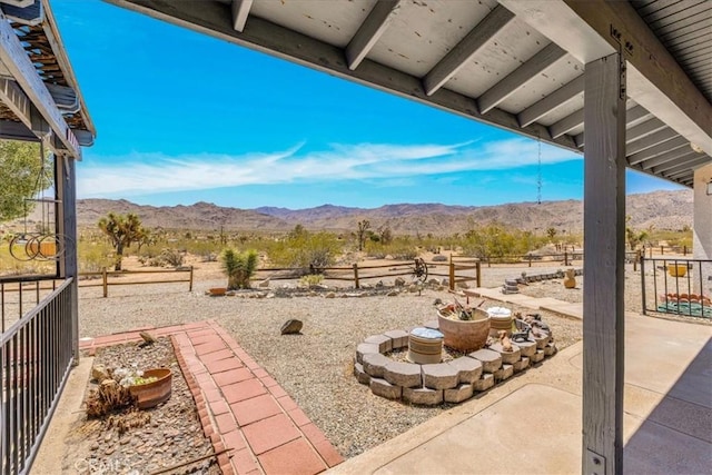 view of patio / terrace featuring fence, a mountain view, and a rural view
