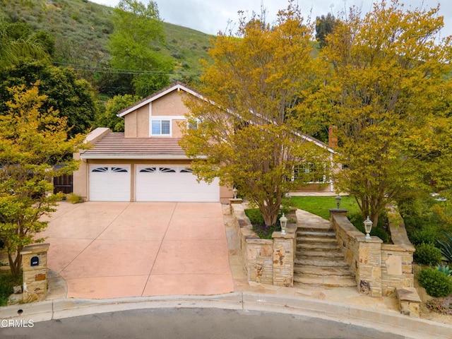 view of front of property with stucco siding, a garage, concrete driveway, and a tile roof