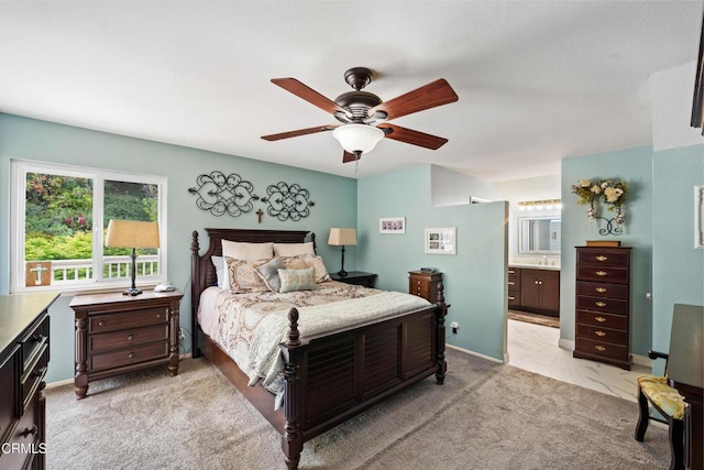 bedroom featuring light carpet, ensuite bath, and ceiling fan