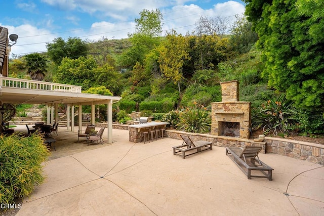 view of patio with an outdoor stone fireplace, stairway, and outdoor dry bar