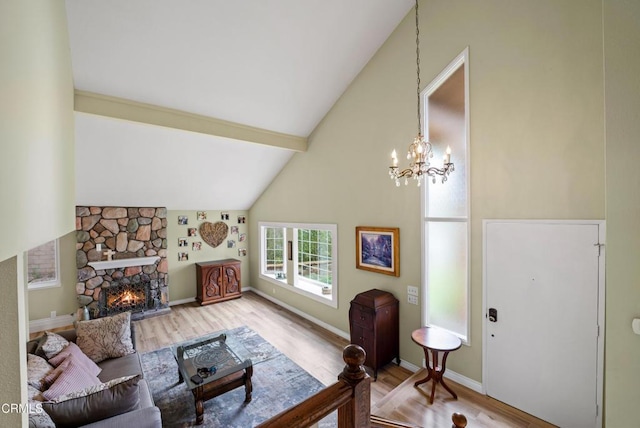 living room with an inviting chandelier, beamed ceiling, a fireplace, light wood-type flooring, and high vaulted ceiling