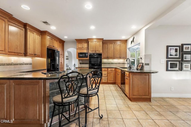 1894 Rambling Rd, Simi Valley, CA 93065 - kitchen featuring black appliances, a peninsula, arched walkways, tasteful backsplash, and brown cabinets