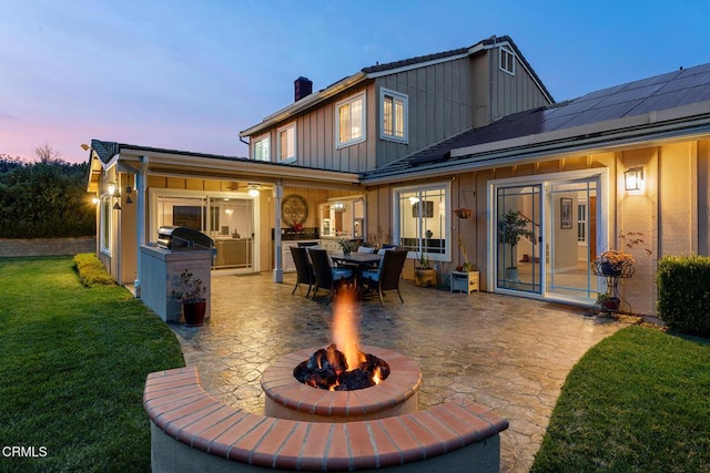 1894 Rambling Rd, Simi Valley, CA 93065 - back of house at dusk with a patio area, board and batten siding, a lawn, a chimney, and area for grilling
