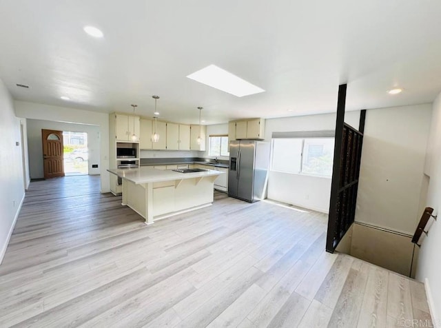 1025 Wilbur Ave, Pacific Beach San Diego, CA 92109 - kitchen featuring light countertops, light wood-style floors, a center island, a skylight, and appliances with stainless steel finishes