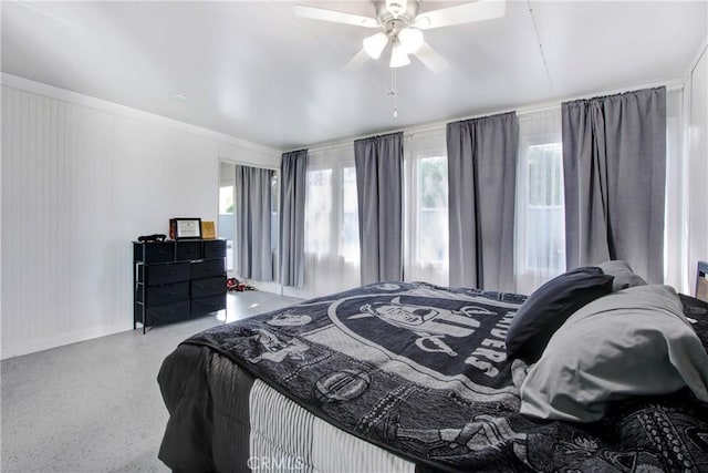 bedroom featuring speckled floor, baseboards, a ceiling fan, and multiple windows