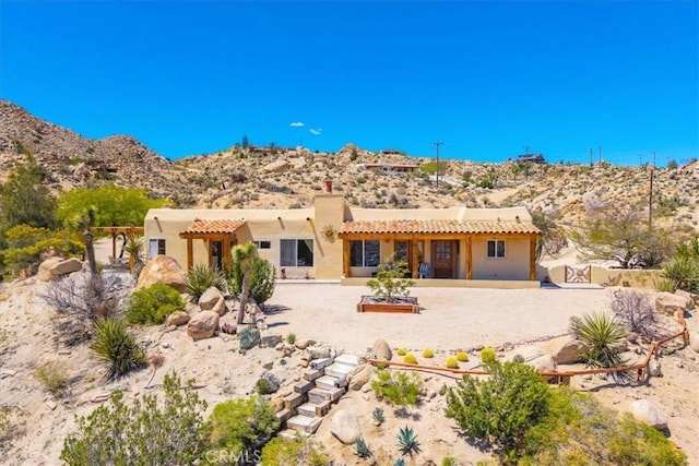 57710 Bandera Rd, Yucca Valley, CA 92284 - rear view of house with a chimney, stucco siding, a mountain view, and a tile roof