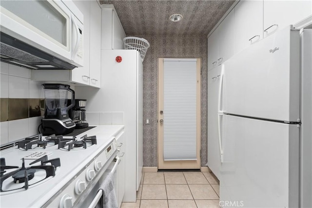kitchen with light countertops, white cabinetry, light tile patterned floors, and white appliances