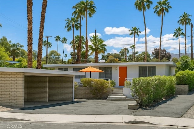 mid-century home with stucco siding, brick siding, and a carport