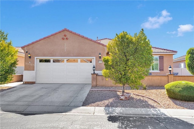 view of front of house featuring a tiled roof, driveway, fence, an attached garage, and stucco siding