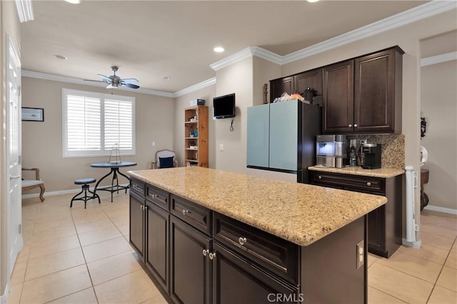 kitchen featuring ceiling fan, baseboards, a center island, and freestanding refrigerator