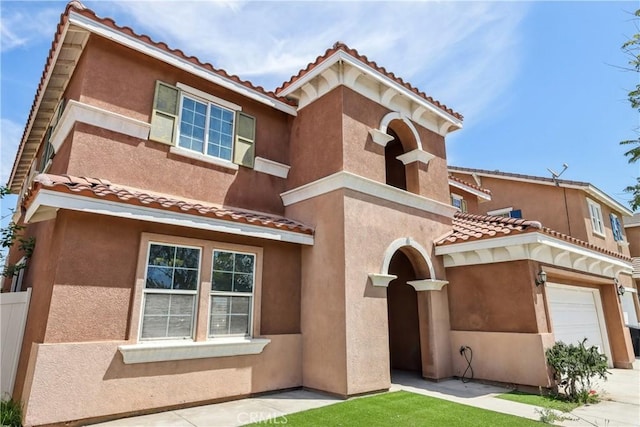 view of front of property with stucco siding, a tile roof, fence, and a garage