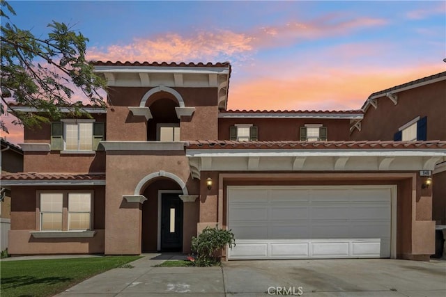 view of front of property featuring stucco siding, a tile roof, a garage, and concrete driveway