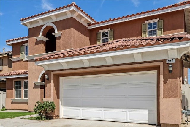 view of front of home featuring concrete driveway, stucco siding, a tiled roof, and a garage