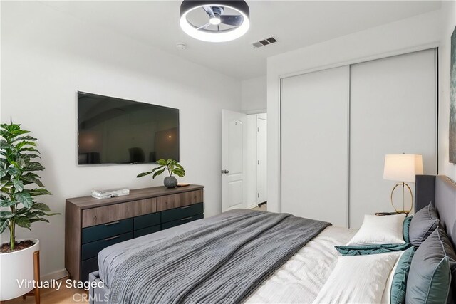 bedroom with wood finished floors, visible vents, and a closet
