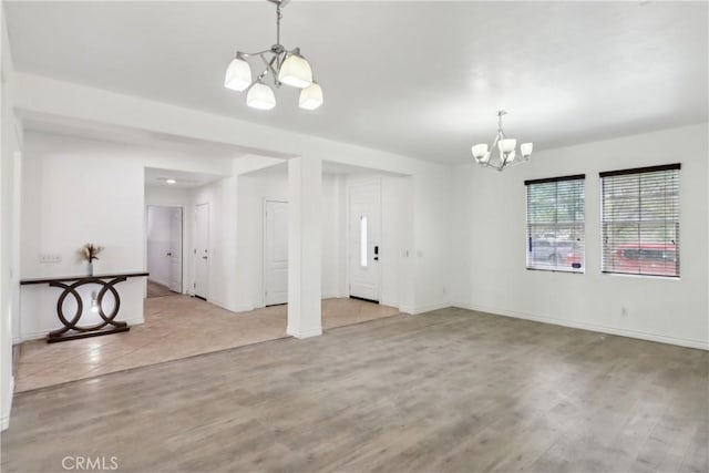 unfurnished dining area with baseboards, wood finished floors, and a chandelier