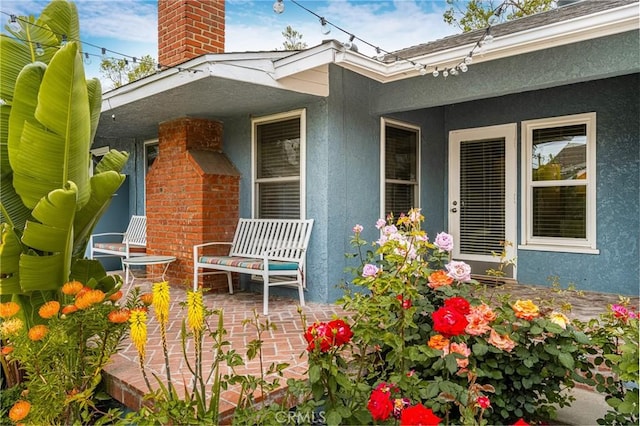 exterior space featuring a porch, a chimney, and stucco siding