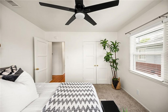 carpeted bedroom with a ceiling fan, visible vents, and a closet