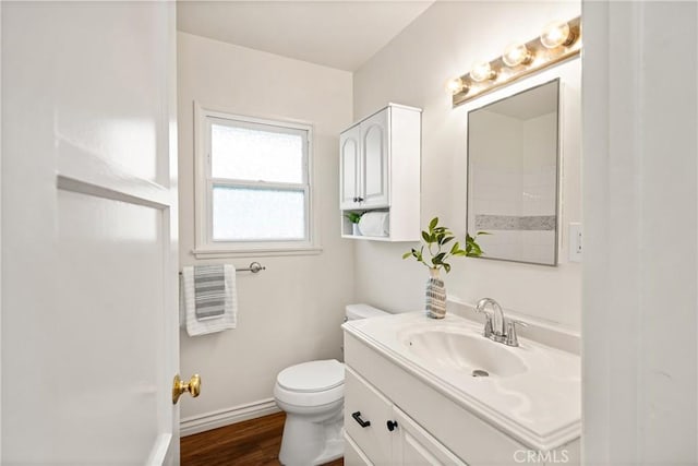 bathroom with baseboards, toilet, vanity, and wood finished floors