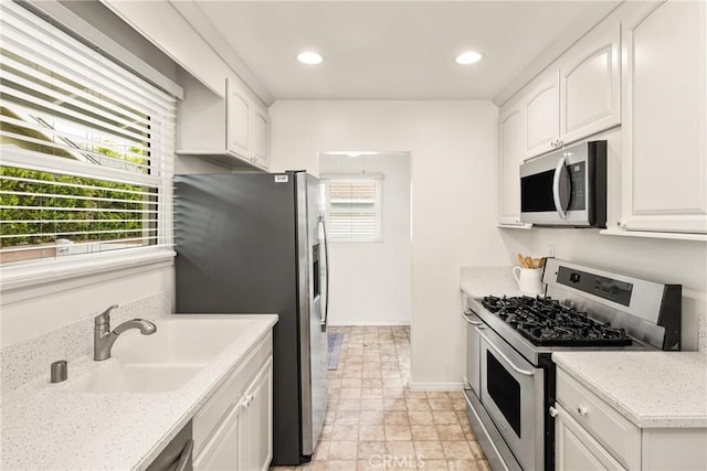 kitchen with white cabinets, recessed lighting, a sink, baseboards, and appliances with stainless steel finishes