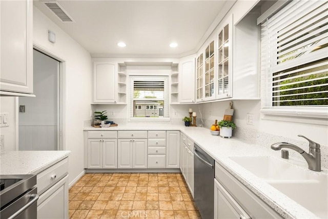 kitchen with white cabinets, open shelves, stone finish floor, visible vents, and stainless steel dishwasher