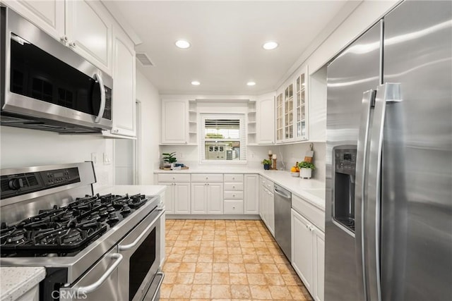 kitchen featuring visible vents, white cabinetry, stone finish floor, open shelves, and appliances with stainless steel finishes