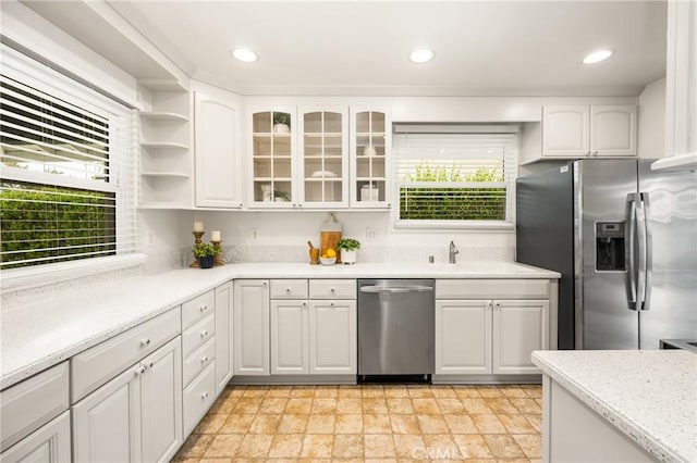 kitchen with white cabinets, glass insert cabinets, a healthy amount of sunlight, and appliances with stainless steel finishes