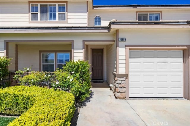 view of exterior entry featuring stone siding and driveway