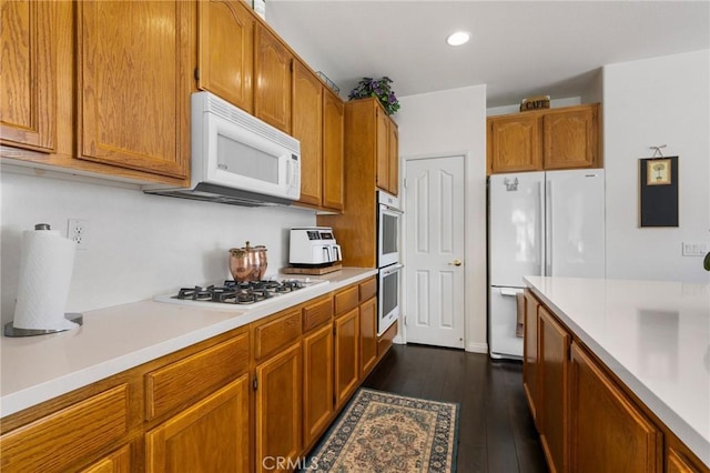 kitchen featuring light countertops, white appliances, and brown cabinets