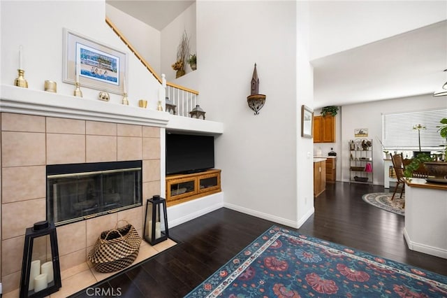 living area with a tile fireplace, baseboards, and dark wood-style flooring