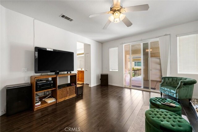 living area featuring baseboards, visible vents, dark wood-style floors, and ceiling fan