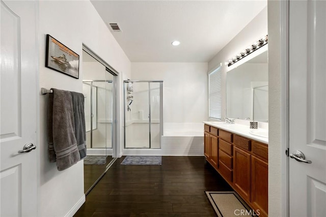 full bathroom featuring double vanity, visible vents, wood finished floors, a shower stall, and a garden tub