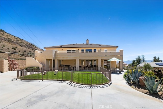 back of house with a patio area, fence, a mountain view, a yard, and stucco siding