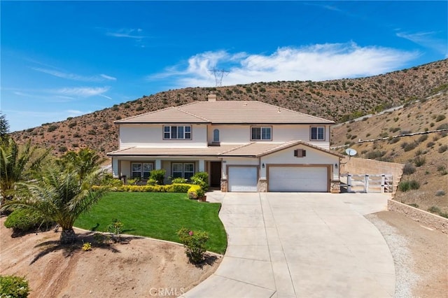 traditional-style home with a tiled roof, a front lawn, a mountain view, driveway, and a chimney
