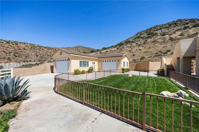 ranch-style home with a front lawn, driveway, fence private yard, an attached garage, and a mountain view
