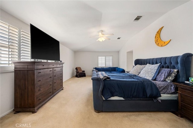 bedroom featuring ceiling fan, vaulted ceiling, visible vents, and light colored carpet