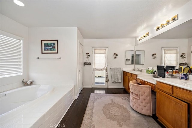 bathroom with plenty of natural light, a garden tub, vanity, and wood finished floors