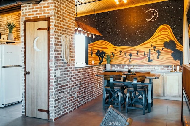 dining space featuring brick wall, concrete flooring, and wooden ceiling