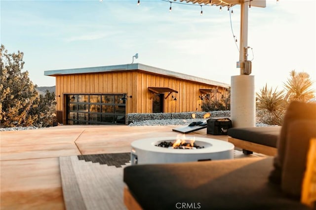 view of patio featuring an outdoor fire pit, concrete driveway, and an attached garage