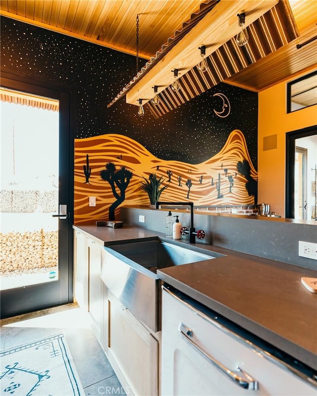kitchen featuring wooden ceiling, dark countertops, white cabinetry, and a sink