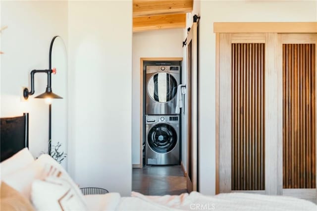 washroom featuring stacked washer and clothes dryer and a barn door